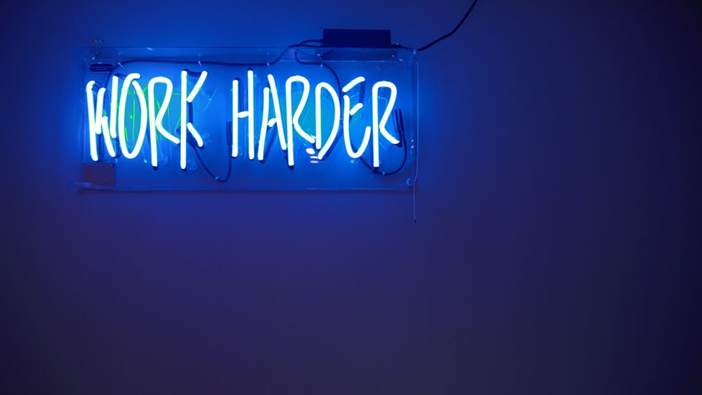 Blue neon sign saying "work harder"