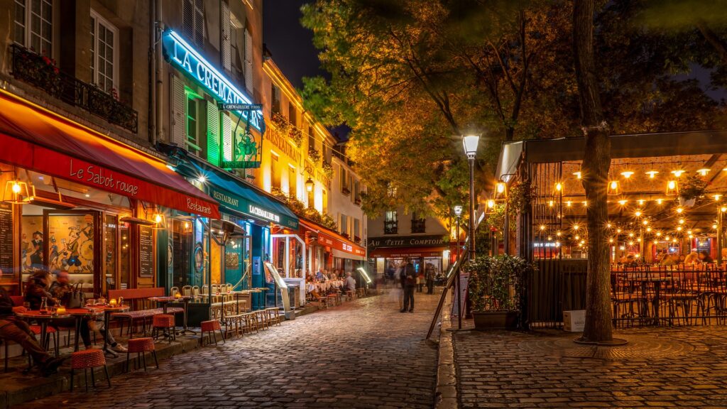 Street in Paris at night with cafes and a guests at tables