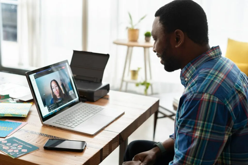 A man in a checked shirt remote working in an office on a virtual call
