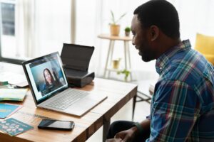 A man in a checked shirt working in an office on a virtual call