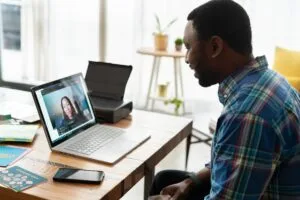 A man in a checked shirt remote working in an office on a virtual call