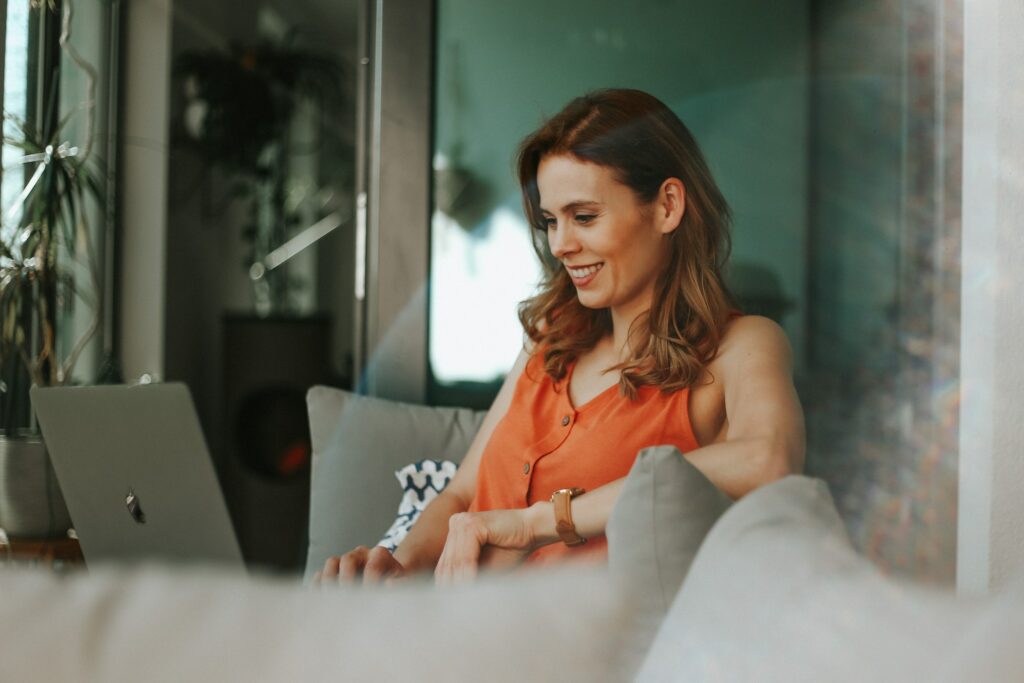 Woman at home on sofa using laptop.