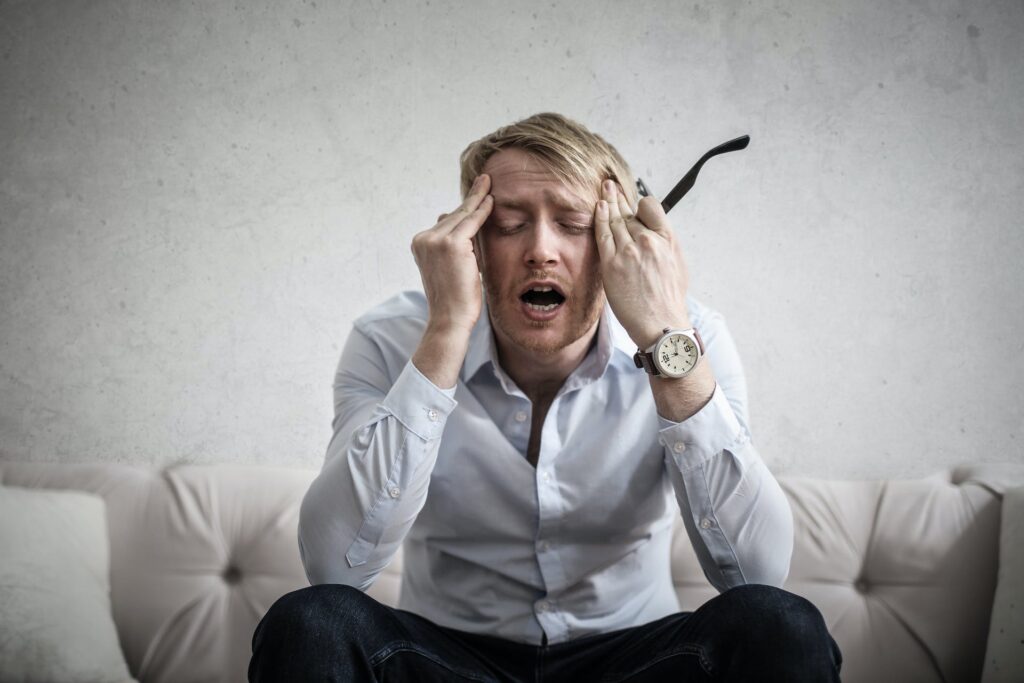 Man sitting down, holding his head with a look of disappointment and frustration.