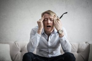 Man sitting down, holding his head with a look of disappointment and frustration.