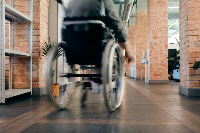 Person in a wheelchair viewed from behind. They are moving away down a corridor.