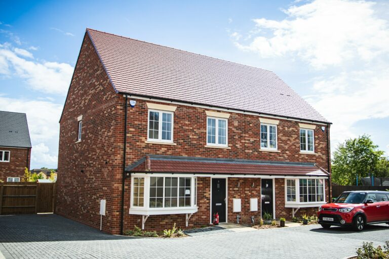 Modern houses (2, semi-detached) with a red car parked in front.