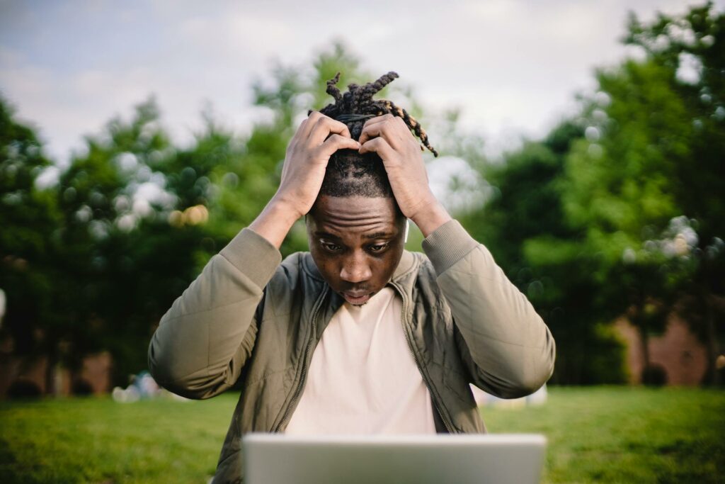 Man looking at laptop and holding is head as he looks stressed