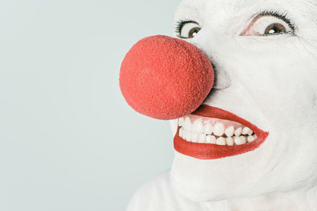 A white clown face with a big red nose.