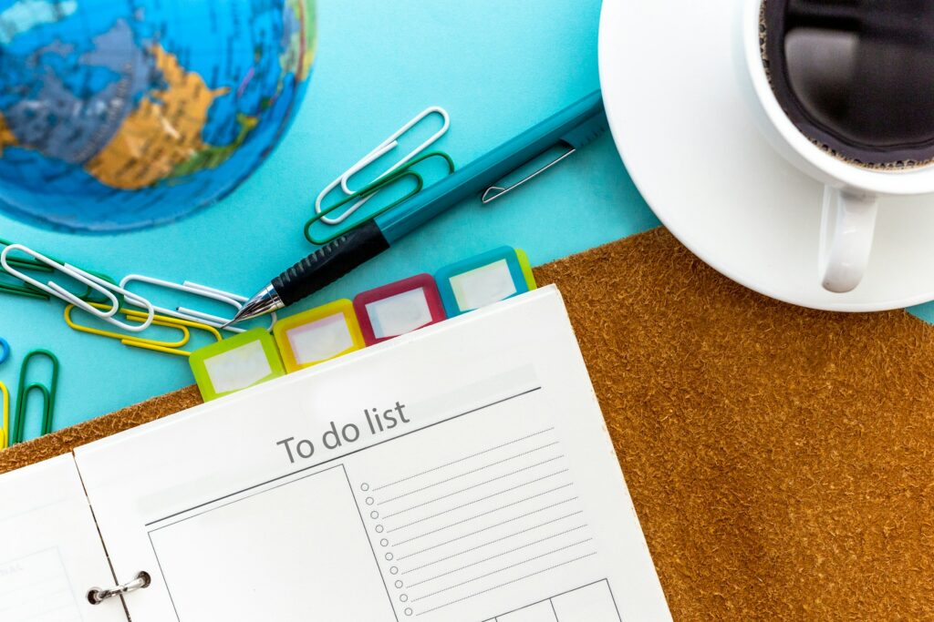 To do list on a table with paperclips, a pen and a cup of coffee. Relocating to the UK checklist.