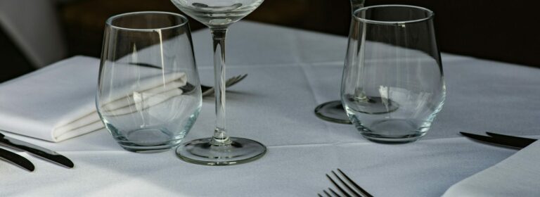 British etiquette: 2 place settings each with napkin, 2 sets of cutlery and a wine and water glass.