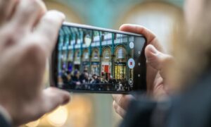 A person captures the vibrant atmosphere of a bustling London marketplace with their UK mobile phone. The photo showcases the intricate architecture and the energy of the crowd.