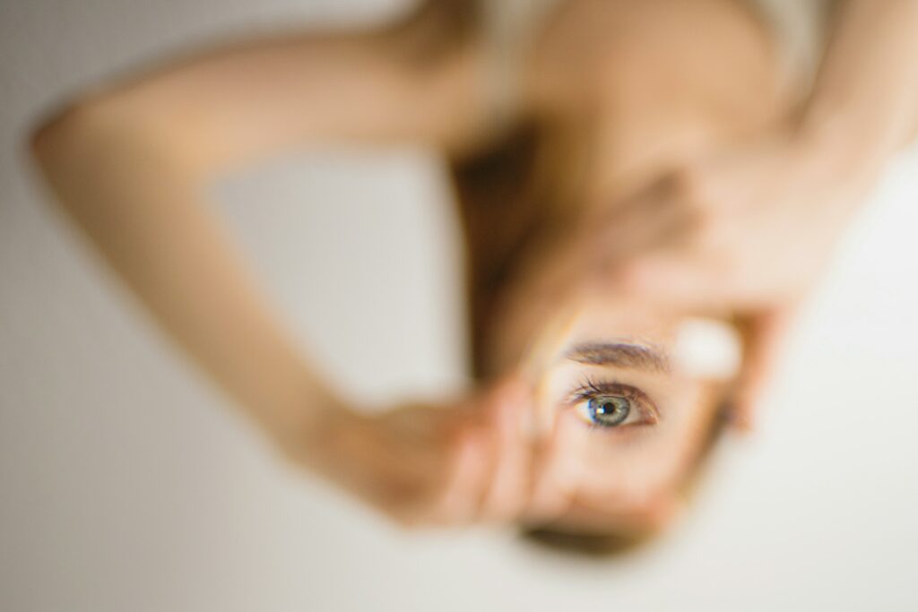 An upside-down close-up of a blue eye reflected in a small mirror held in a person's hand