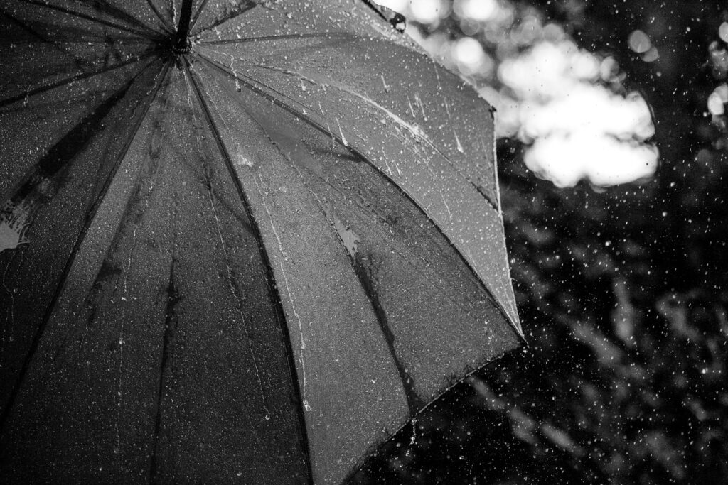 A close-up of a wet umbrella with rain falling in the background, capturing the essence of a typical British rainy day.