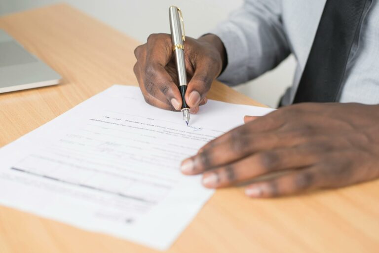 Close-up of a person's hands signing a contract with a fountain pen.