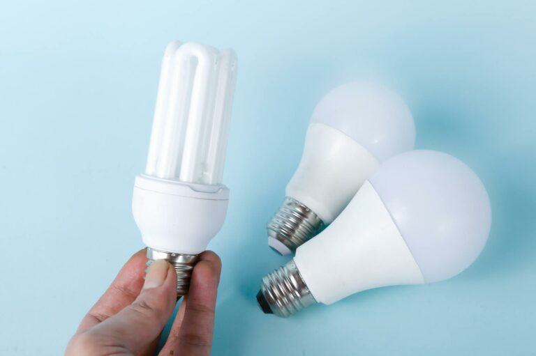 3 energy-efficient lightbulbs. A hand is holding one of them.