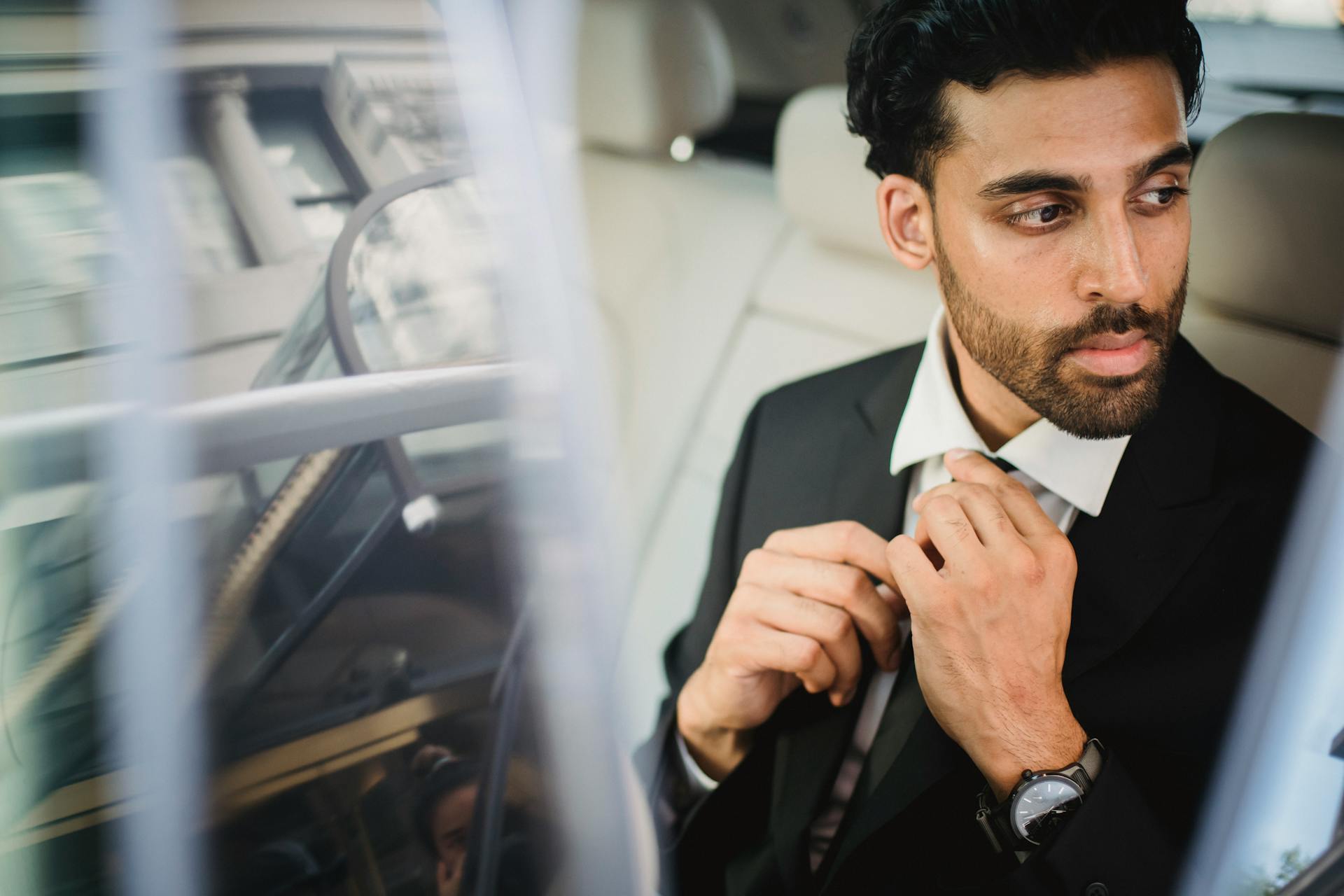 Man in Black Suit Jacket Holding His Necktie