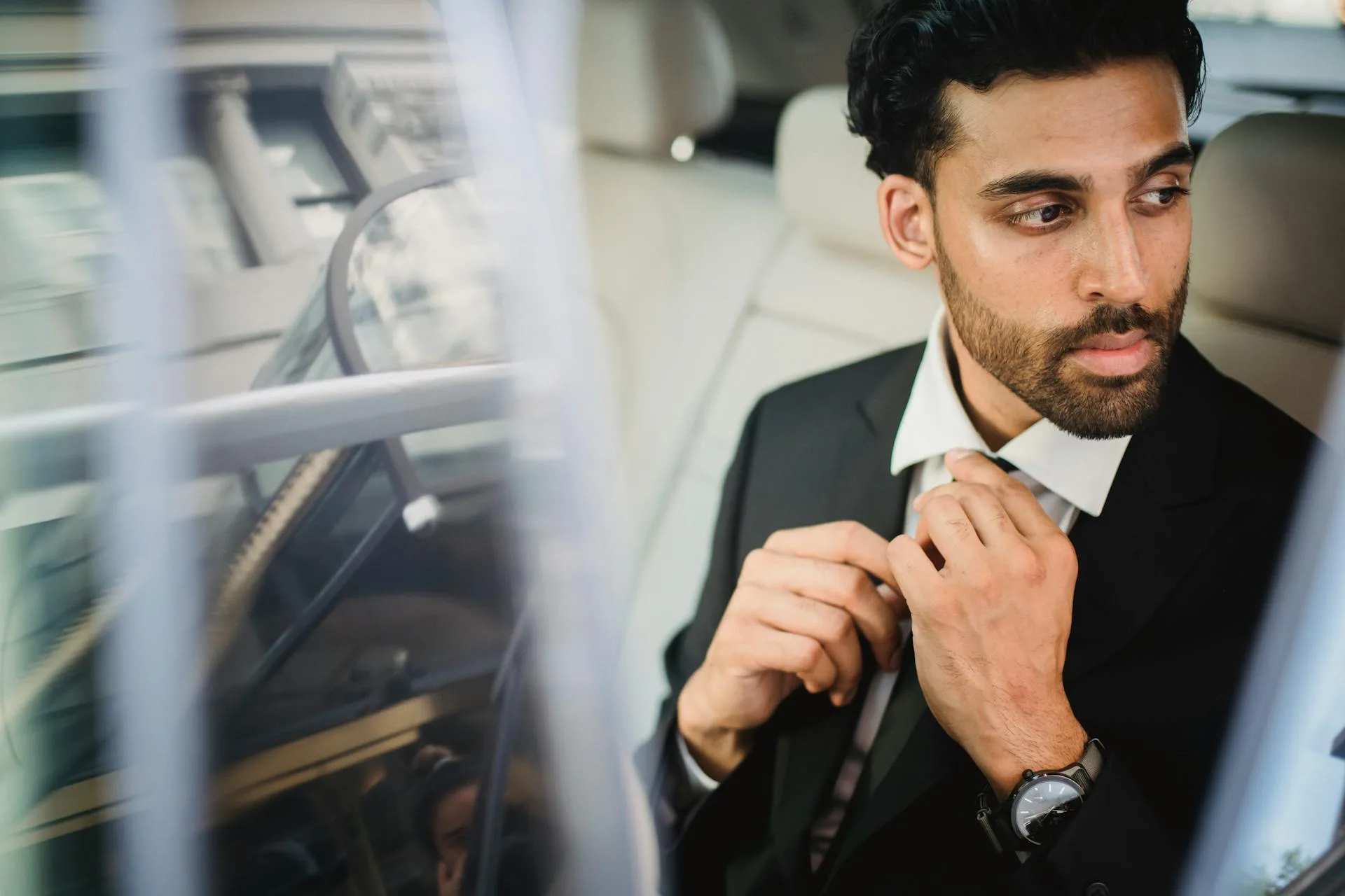Man in Black Suit Jacket Holding His Necktie