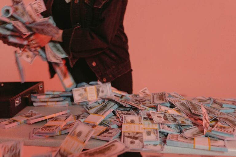 Person in dark clothing dropping stacks of US dollar bills, with currency scattered across pink background, depicting financial wrongdoing.